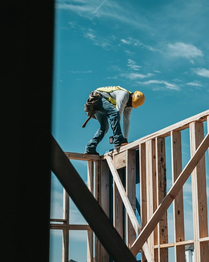 Framer in a hard hat working along the top plate of a new wood-framed wall